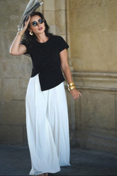 a lady in a black asymmetrical top and a pair of white wide leg pants